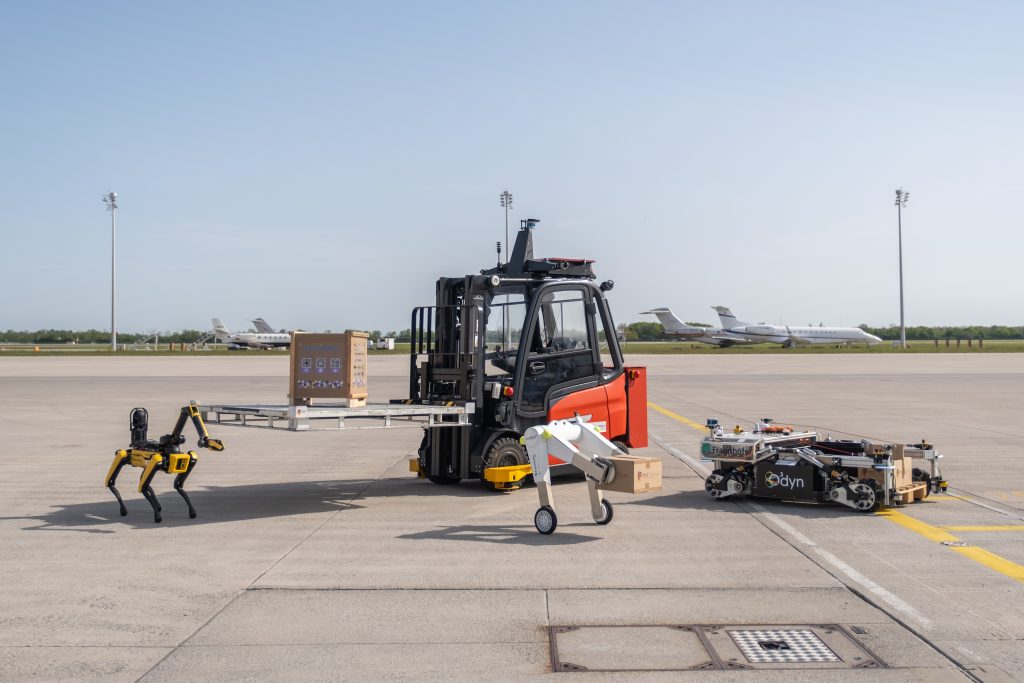 Drei Roboter und ein Gabelstapler auf dem Flugfeld in München