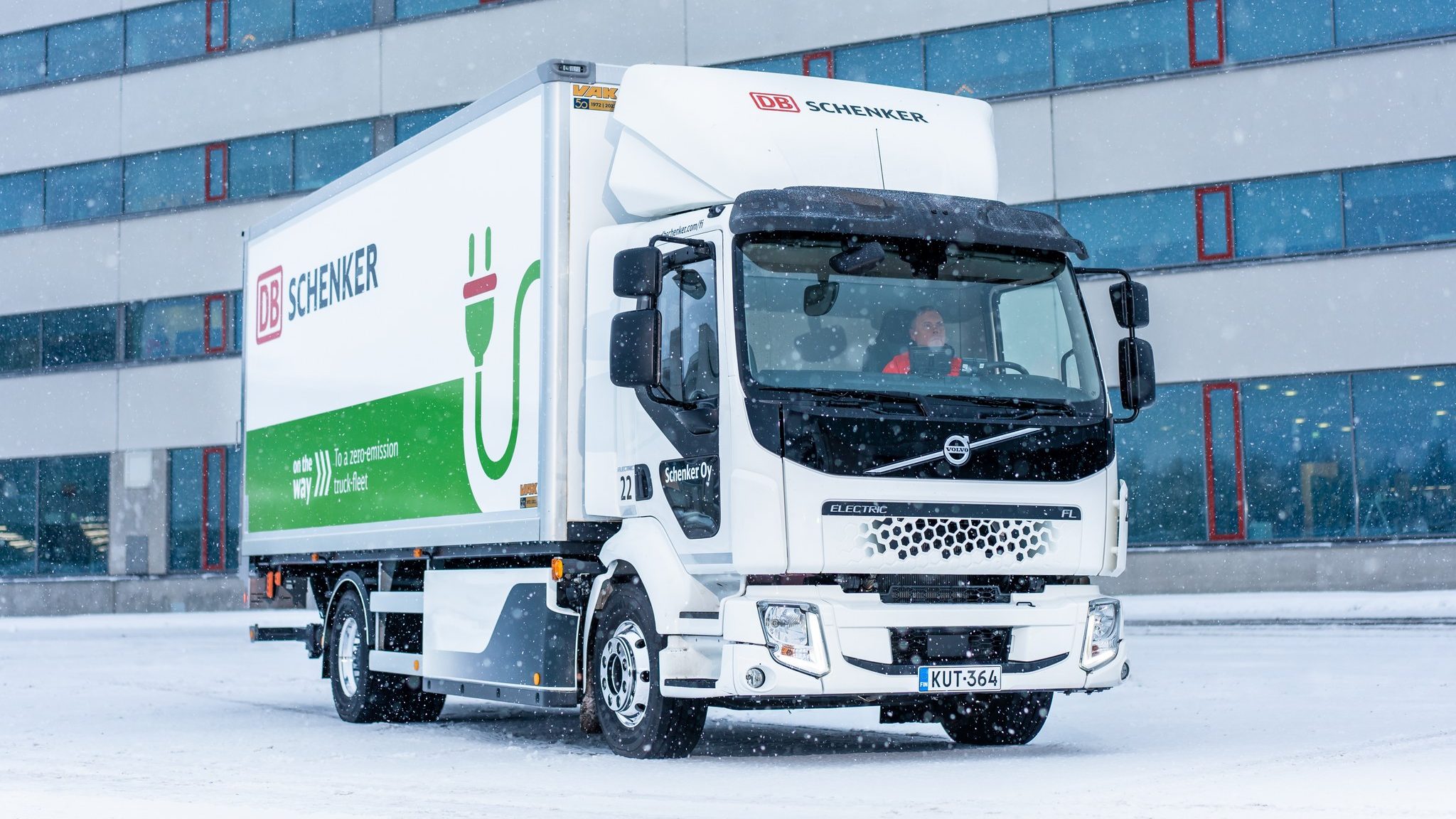 Volvo FL Electric -kuorma-auto DB Schenkerin toimistorakennuksen edessä kevyessä lumisateessa.