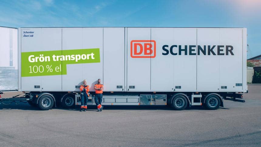 En kvinna och en man i reflexkläder står lutade mot en stor lastbil av grön transport med DB Schenker-logo.