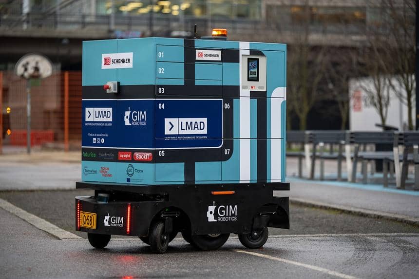 Stor leveransrobot med loggor som levererar paket åker på motorvägen. 