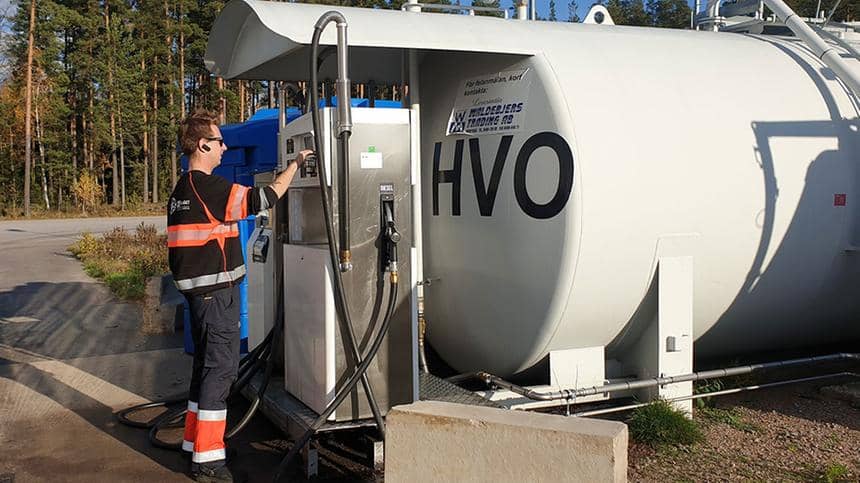 En man i arbetskläder står framför tanken med HVO-bränsle. 
