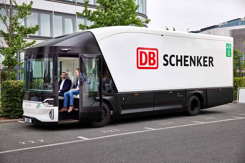 Två män sitter i förarhytten på en stor ellastbil med DB Schenker-logo.